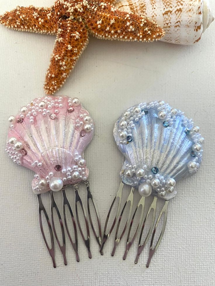 two hair combs with pearls on them next to a starfish and seashell