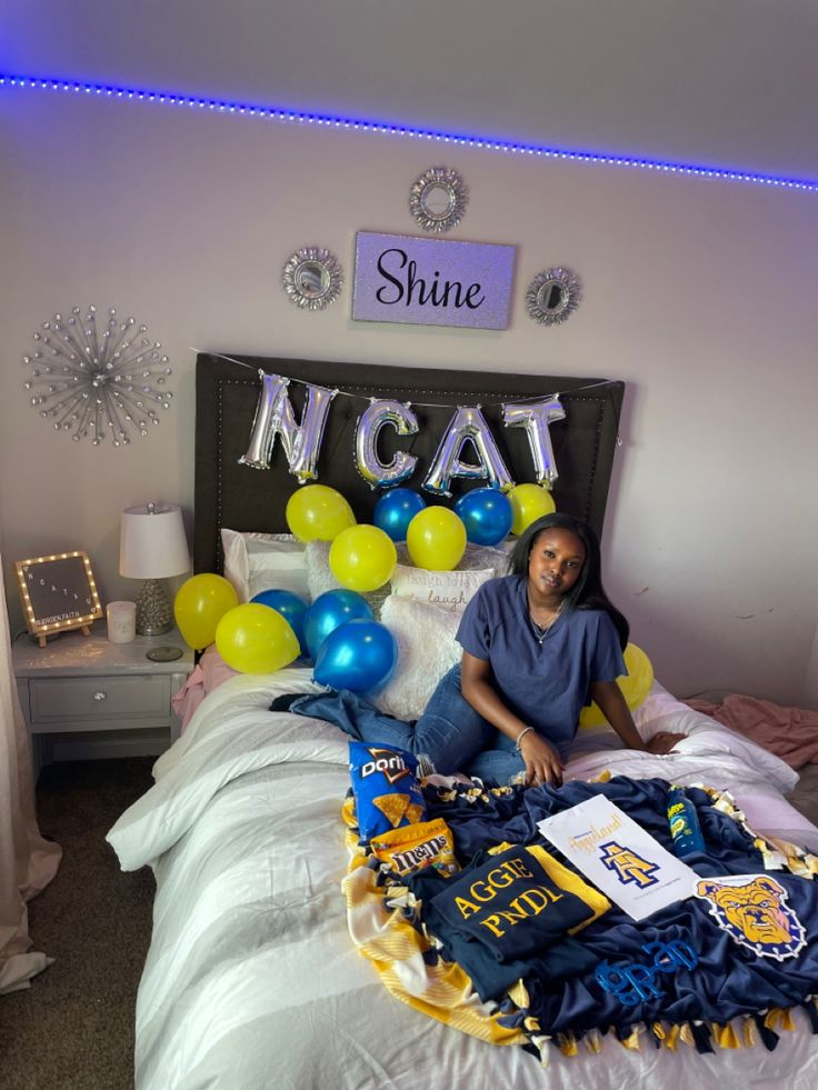 a woman sitting on top of a bed in a room with blue and yellow balloons