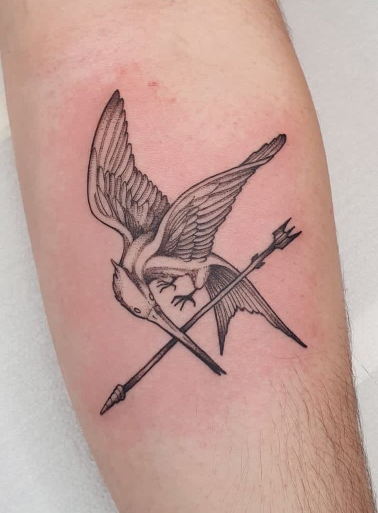 a black and white tattoo of a bird with an arrow on it's arm