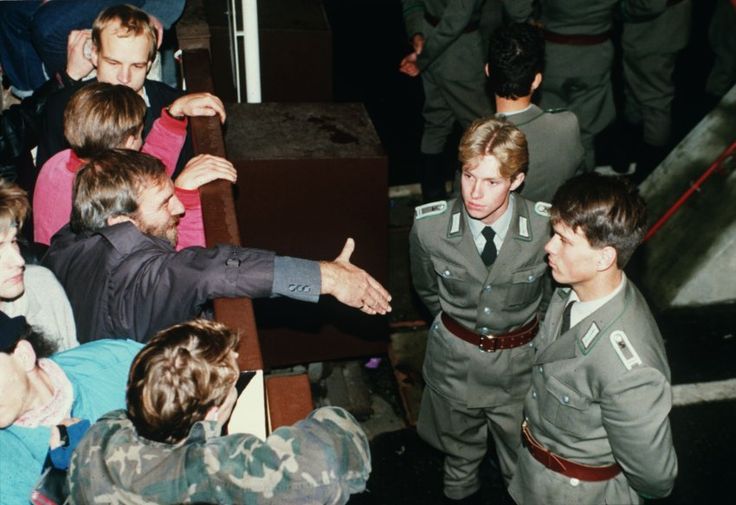 a group of people standing around each other in front of a man pointing at something