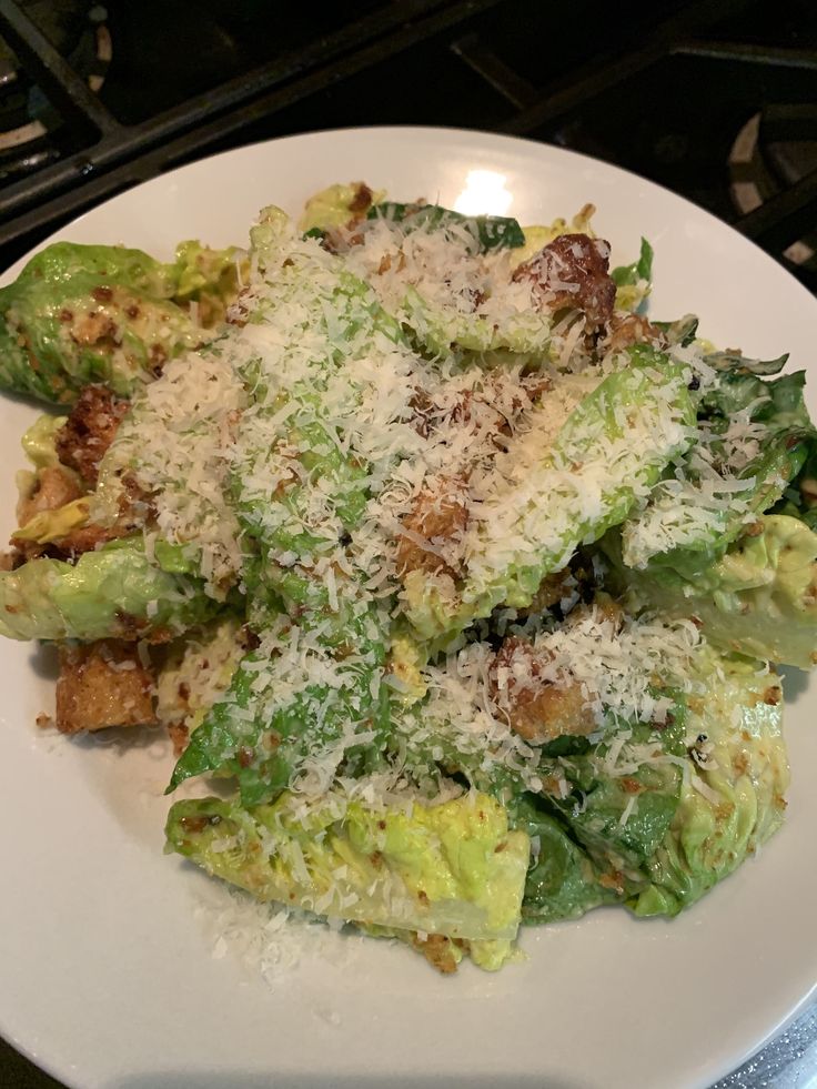 a white plate topped with broccoli covered in parmesan cheese