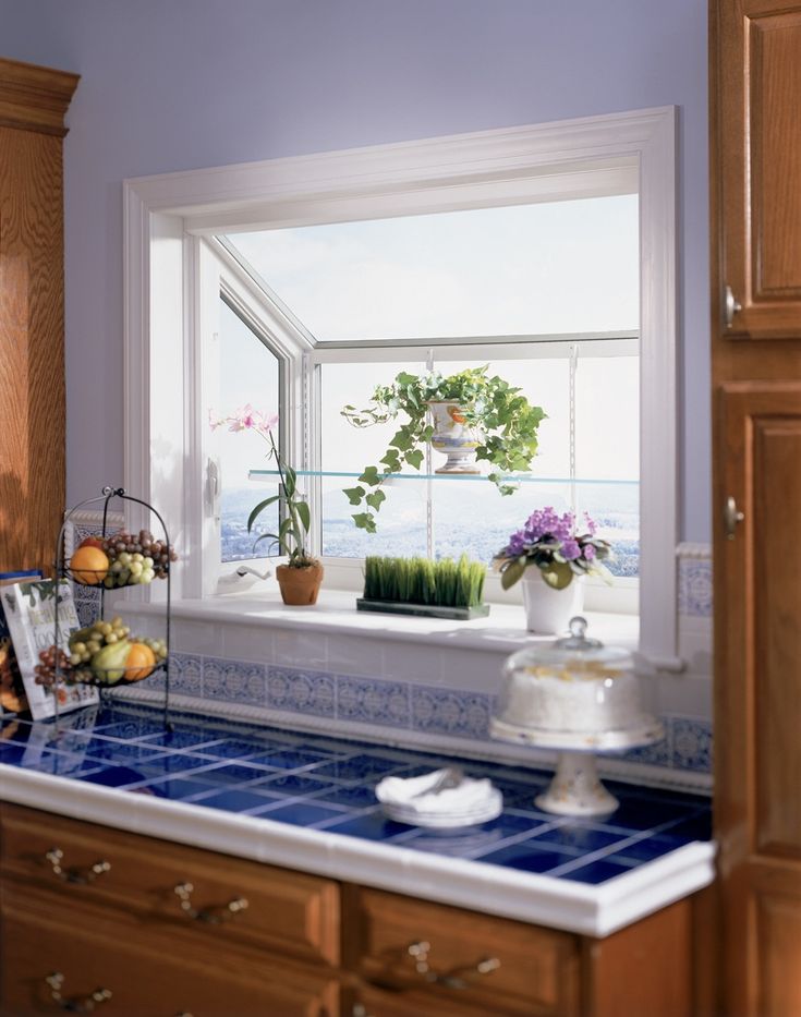 a kitchen window with potted plants on the ledge and in front of it is a blue tiled countertop