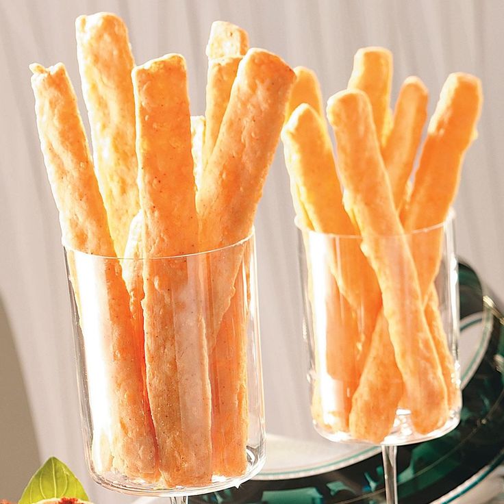 there are several small glass cups with food in them on the tray and one is filled with cheese sticks