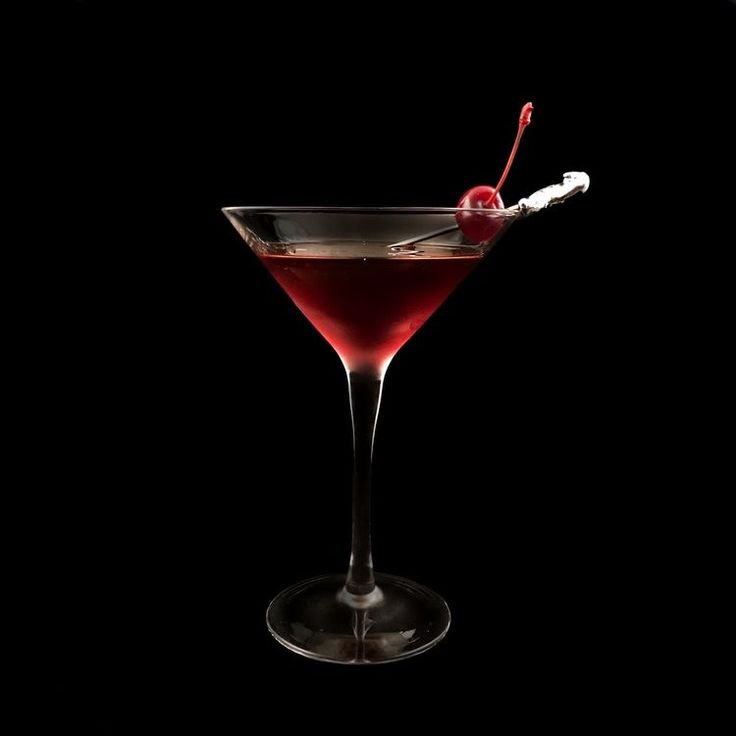 a red drink in a martini glass with a cherry on the rim