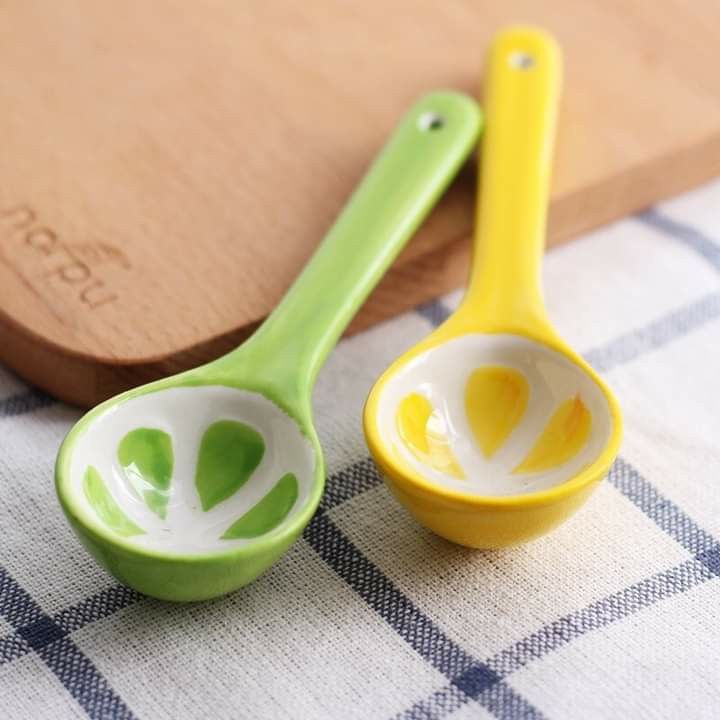 two yellow and green spoons sitting on top of a table