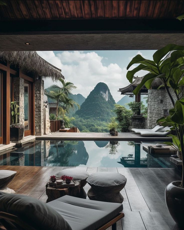 an outdoor swimming pool with mountains in the background and lounge chairs on the deck area