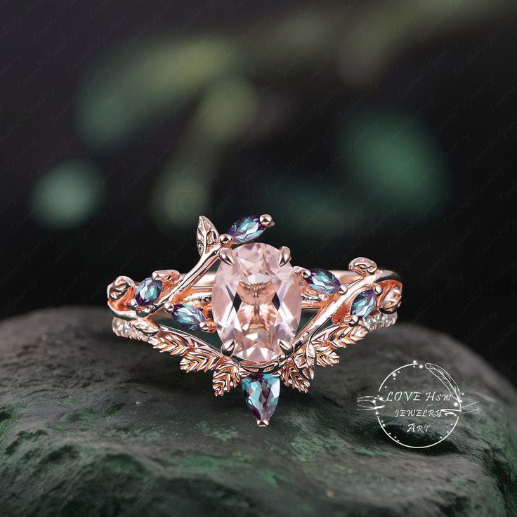 an engagement ring with pink and blue stones on top of a green mossy rock