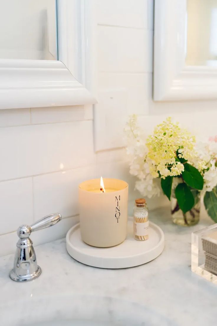 a white candle sitting on top of a bathroom counter