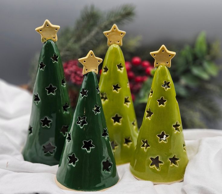 three green ceramic christmas trees with gold stars on them, sitting next to each other