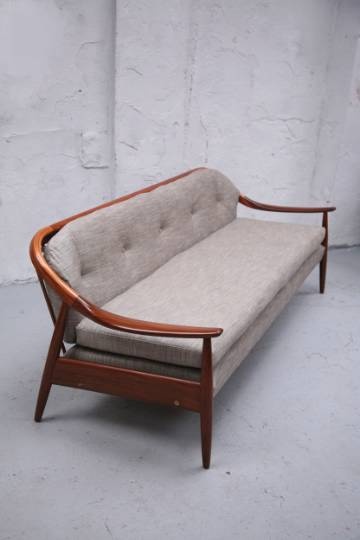 a couch sitting on top of a white floor next to a wall with a wooden frame