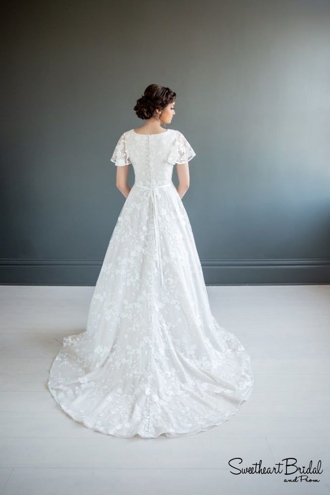 a woman in a white wedding dress looking off into the distance with her back to the camera