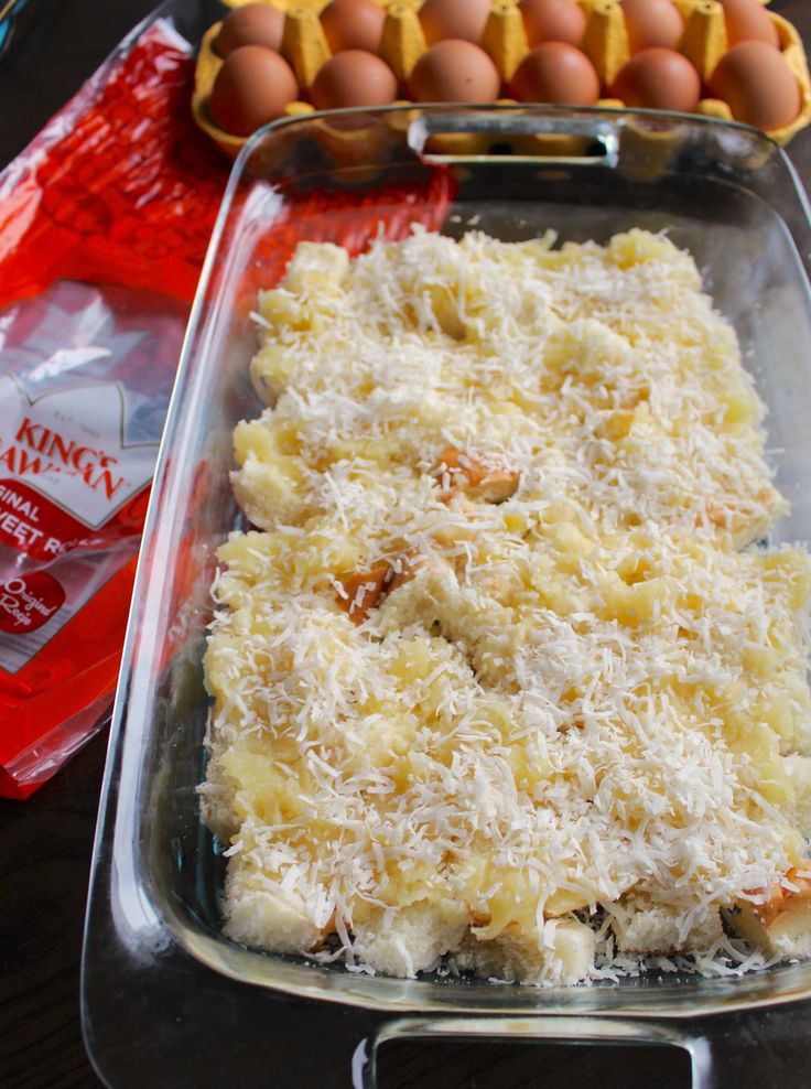 an uncooked casserole dish with cheese and eggs in the back ground