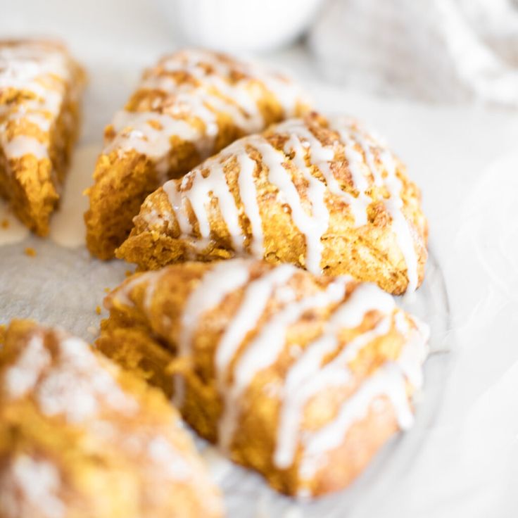 several pastries with icing sitting on a glass plate