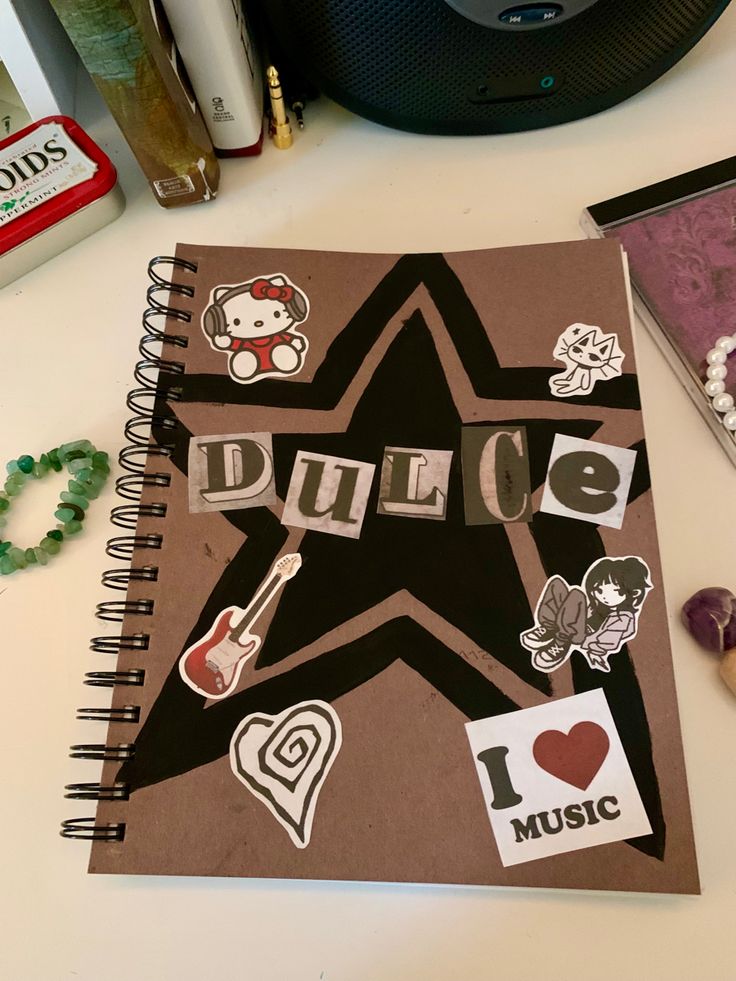 a spiral notebook with stickers on it sitting next to other items and accessories,