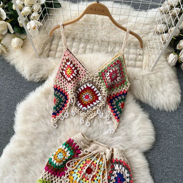 two pieces of crocheted clothing sitting on top of a white fur covered floor