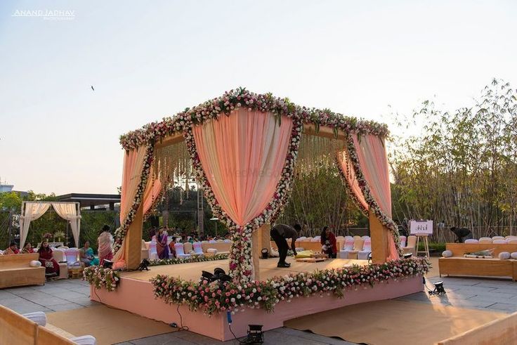 an outdoor wedding setup with pink draping and flowers on the stage for guests to sit down