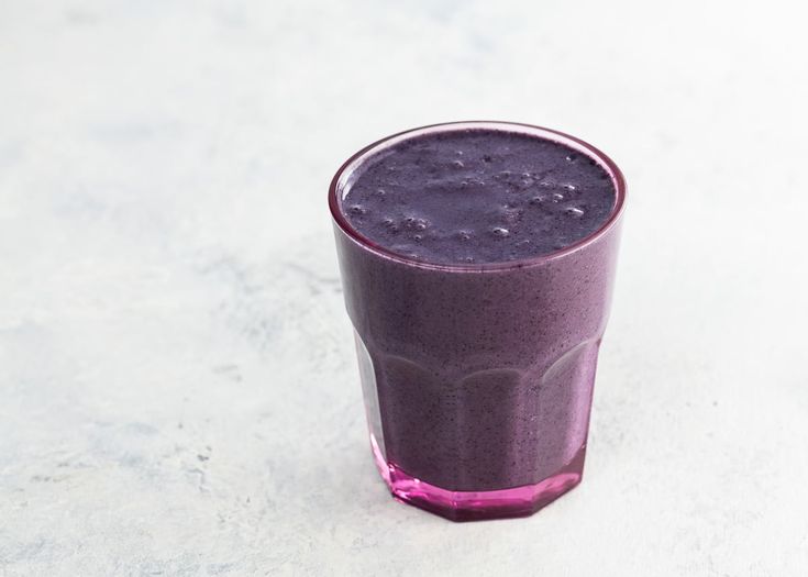 a glass filled with purple liquid sitting on top of a table