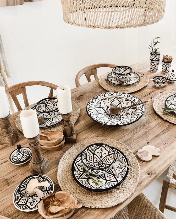 a wooden table topped with lots of plates and place settings next to a wicker chandelier