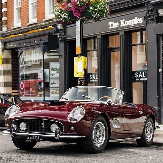 an old red sports car parked on the street