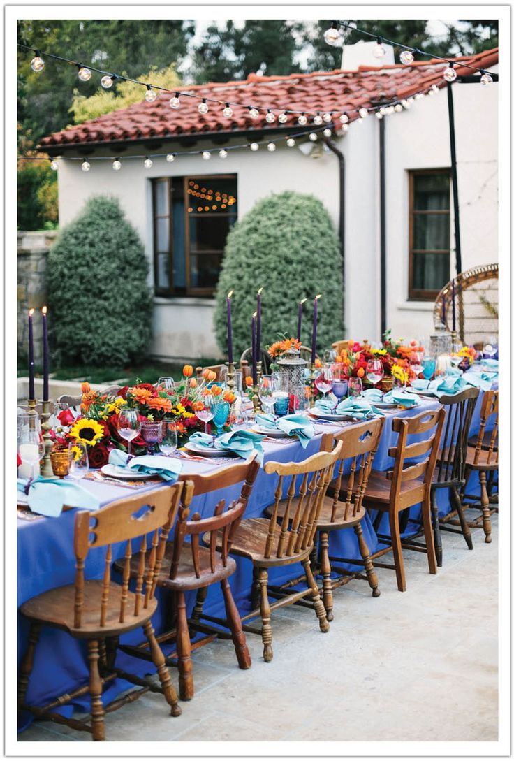 an outdoor dining table set with blue linens and sunflowers