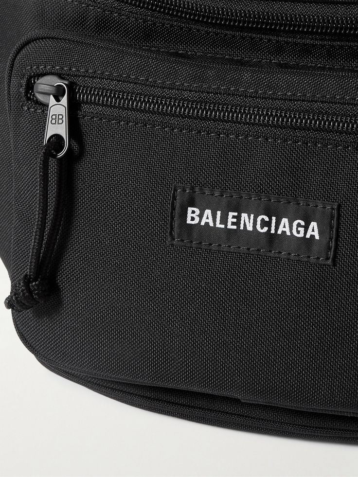 Balenciaga's 'Explorer' belt bag is as practical as it is cool. Made from canvas, it's fitted with two zipped pouches to organise your belongings and has an adjustable fastening. Wear it around your waist or slung over one shoulder. Designer Belt Bag With Adjustable Strap For Travel, Designer Travel Belt Bag With Zipper Closure, Designer Belt Bag For Travel With Zipper, Designer Belt Bag With Zipper Closure For Travel, Luxury Belt Bag With Zipper Pocket For Travel, Luxury Black Belt Bag With Zipper Pocket, Designer Travel Bag With Removable Belt, Designer Black Belt Bag With Belt Loops, Designer Black Belt Bag With Removable Belt