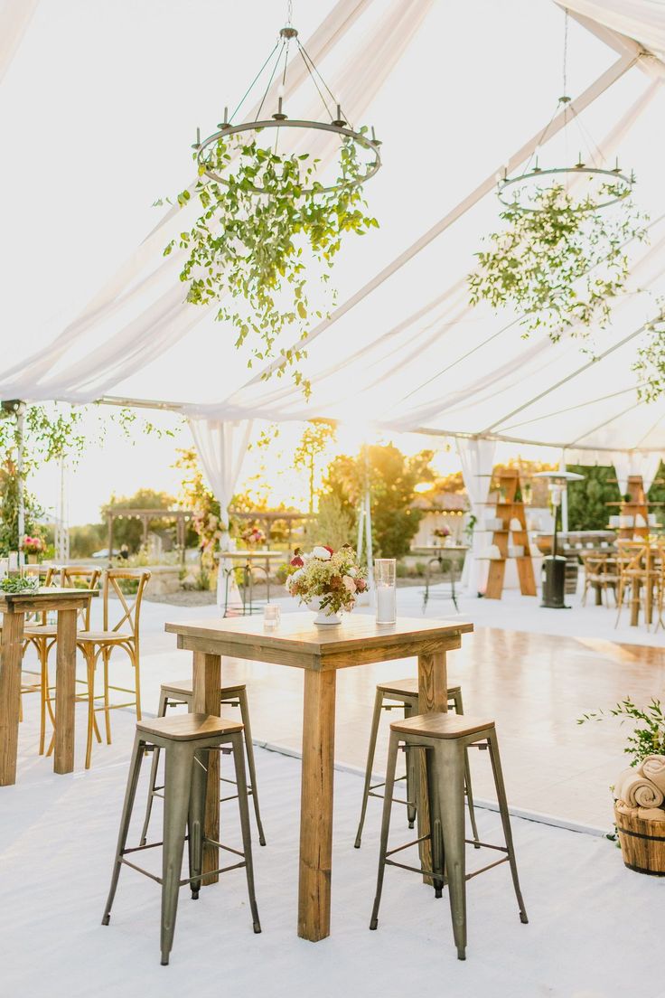 an outdoor event with tables, chairs and hanging plants in the middle of the tent