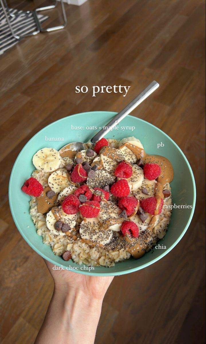 a bowl of oatmeal topped with bananas, raspberries and chocolate chips