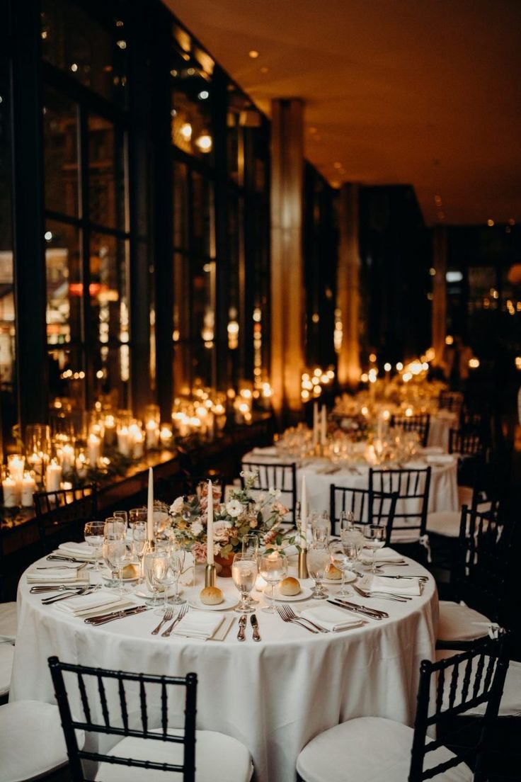 the tables are set with candles and place settings for an elegant dinner or reception at night