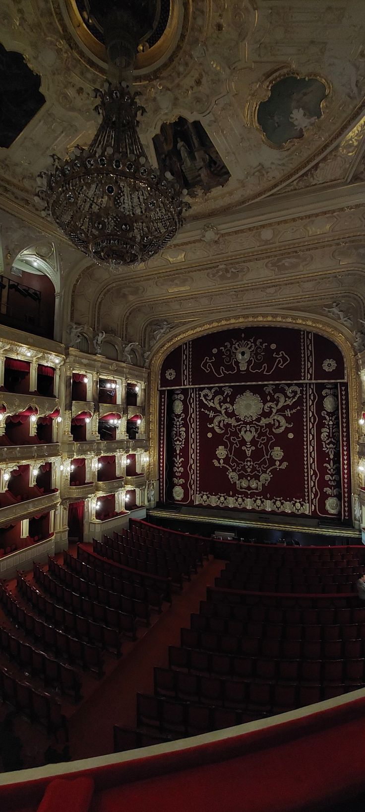 an empty theater with red seats and chandelier