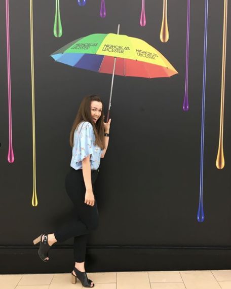 a woman standing in front of a wall with an umbrella painted on it and raindrops hanging from the ceiling