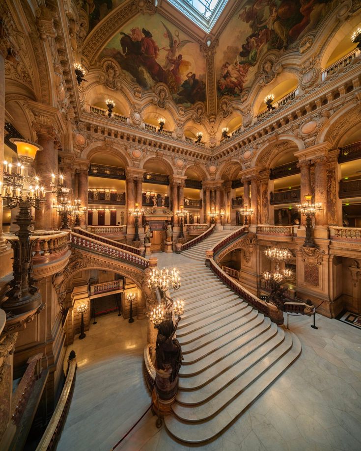 the inside of a large building with many stairs and chandeliers on each floor