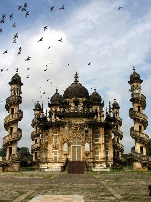 many birds flying in the sky over an old building