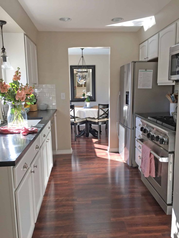 a kitchen with white cabinets and stainless steel appliances, along with hardwood flooring in the middle