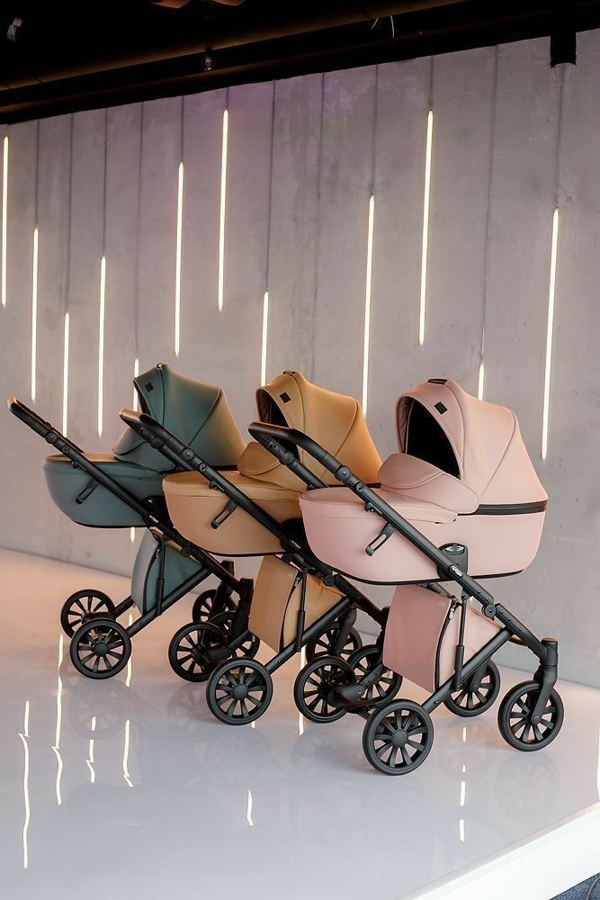 three baby strollers sitting side by side on a white surface with lights in the background