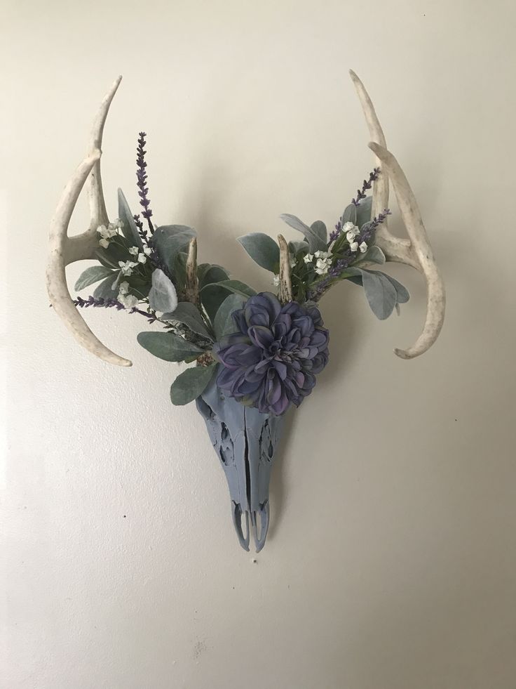 a deer skull with flowers and antlers on the wall