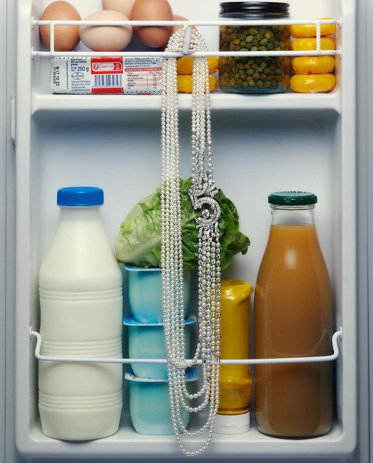 an open refrigerator filled with lots of food and drink bottles next to eggs, carrots, milk, and other items