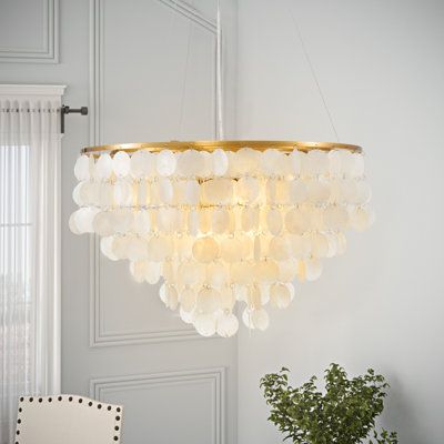 a chandelier hanging from the ceiling over a table with a potted plant