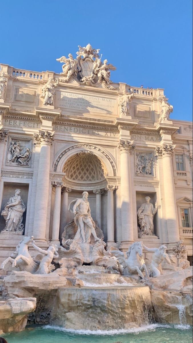 an ornate building with statues and fountains in front