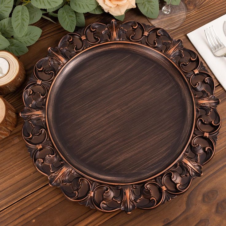 an ornately decorated plate sits on a wooden table next to some candles and flowers