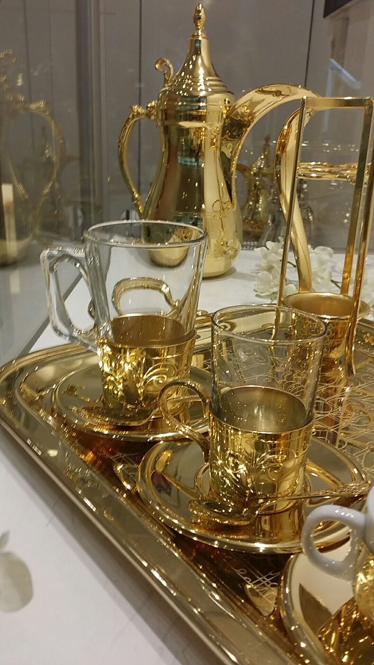 there is a gold tray with cups and saucers on it