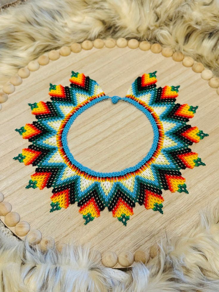 a circular beaded object on top of a wooden table with white fur around it