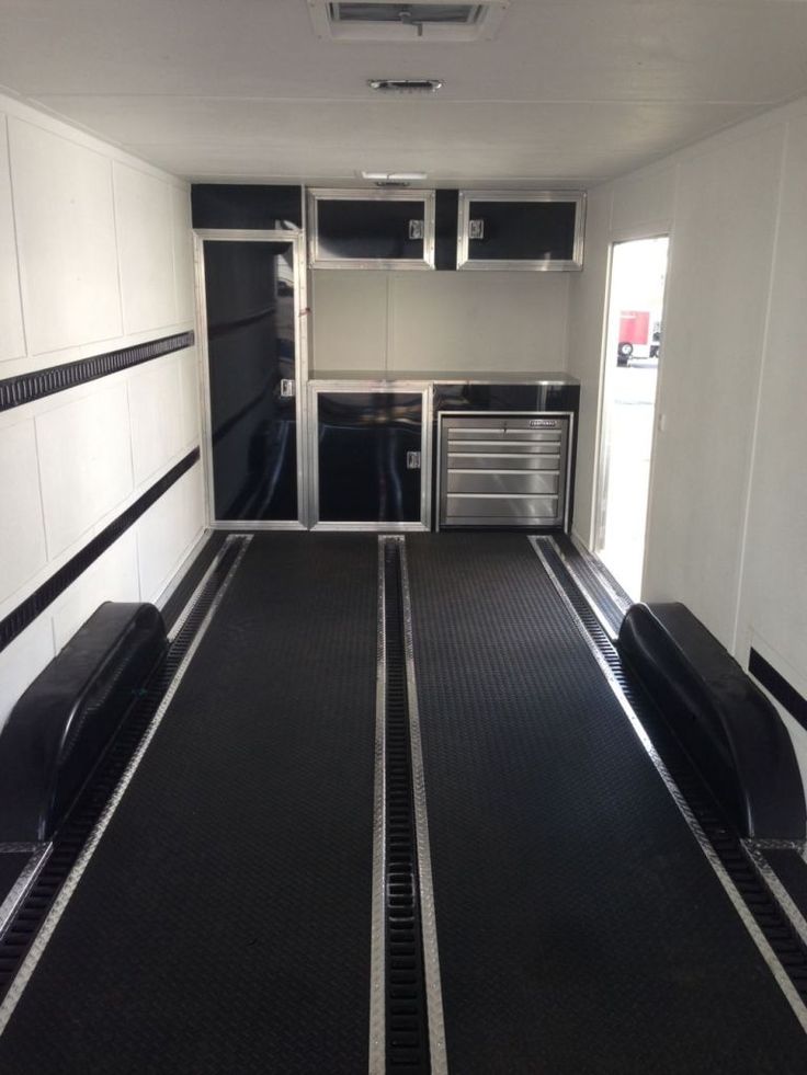 the inside of a trailer with black and white lines on the floor, doors open