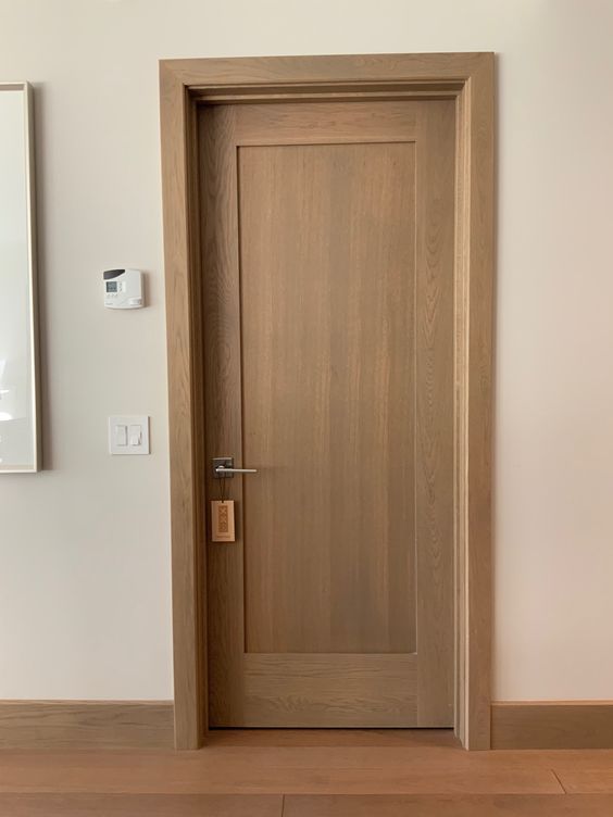 an empty room with a wooden door and light switch on the wall next to it