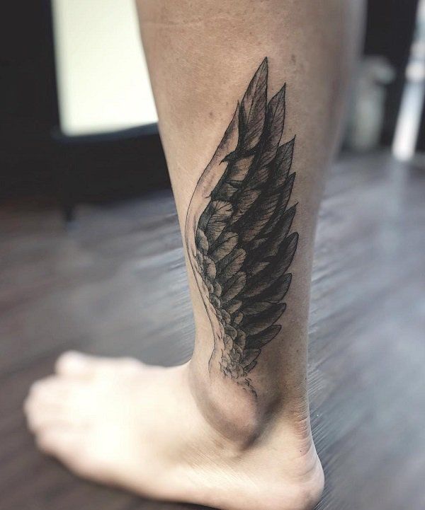 a black and white photo of a person's foot with an angel wing tattoo on it