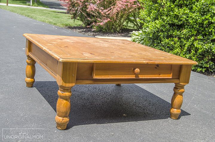 a wooden table sitting on the side of a road next to some bushes and trees