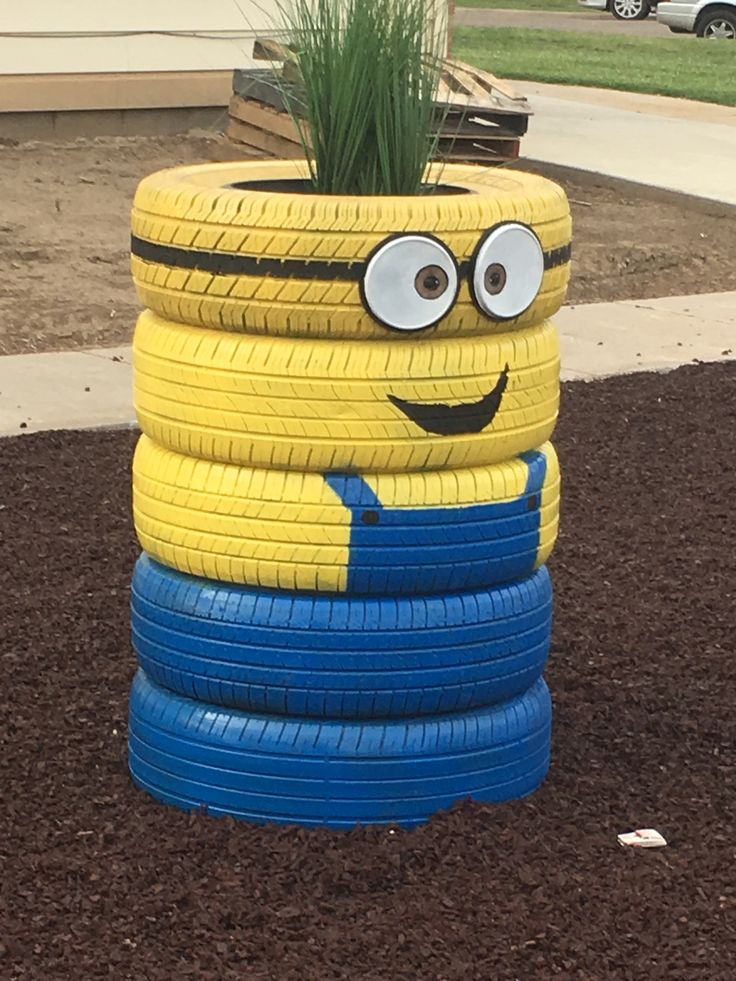 a stack of tires with a plant in the middle and eyes painted on them,