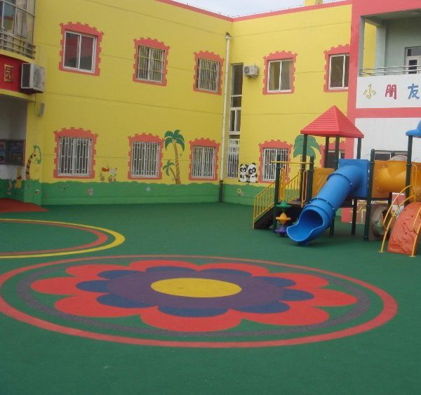 children's play area in front of multi - colored building with slide and playground equipment