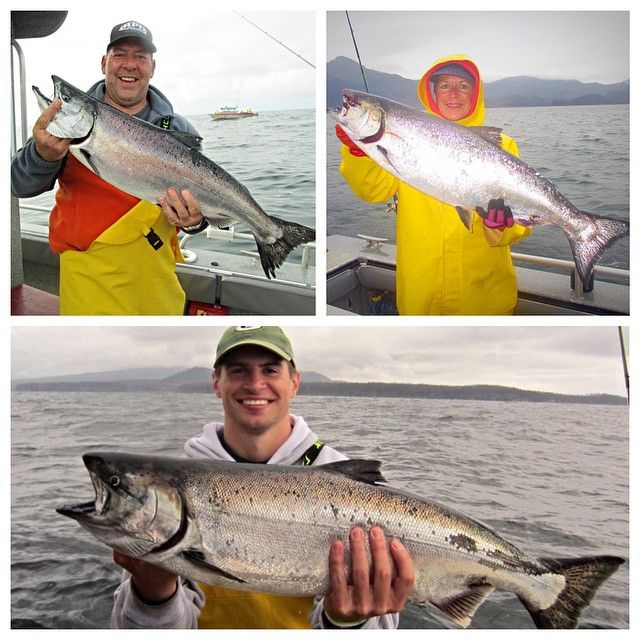 two men holding fish in their hands while standing on a boat