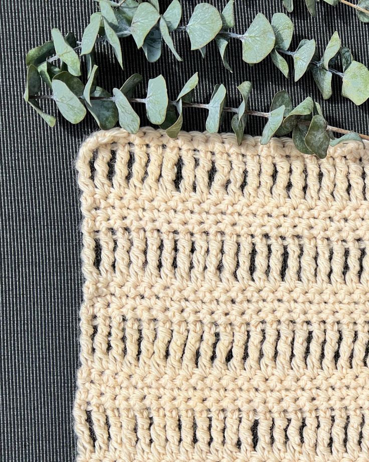 a crocheted placemat with green leaves on the edge and another piece of yarn next to it