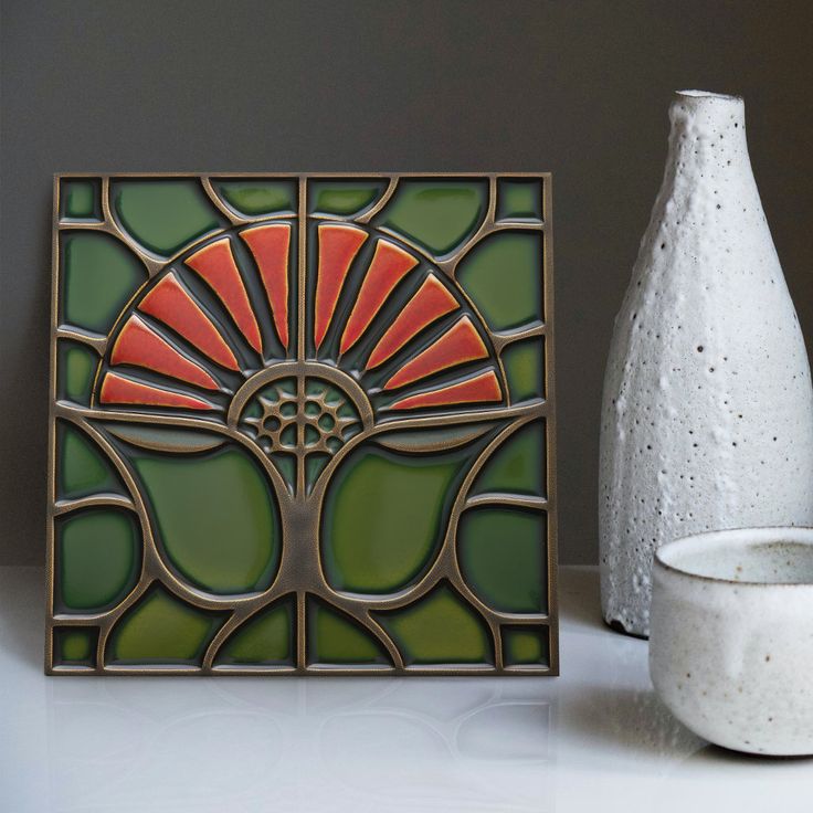 a white vase sitting next to a stained glass piece